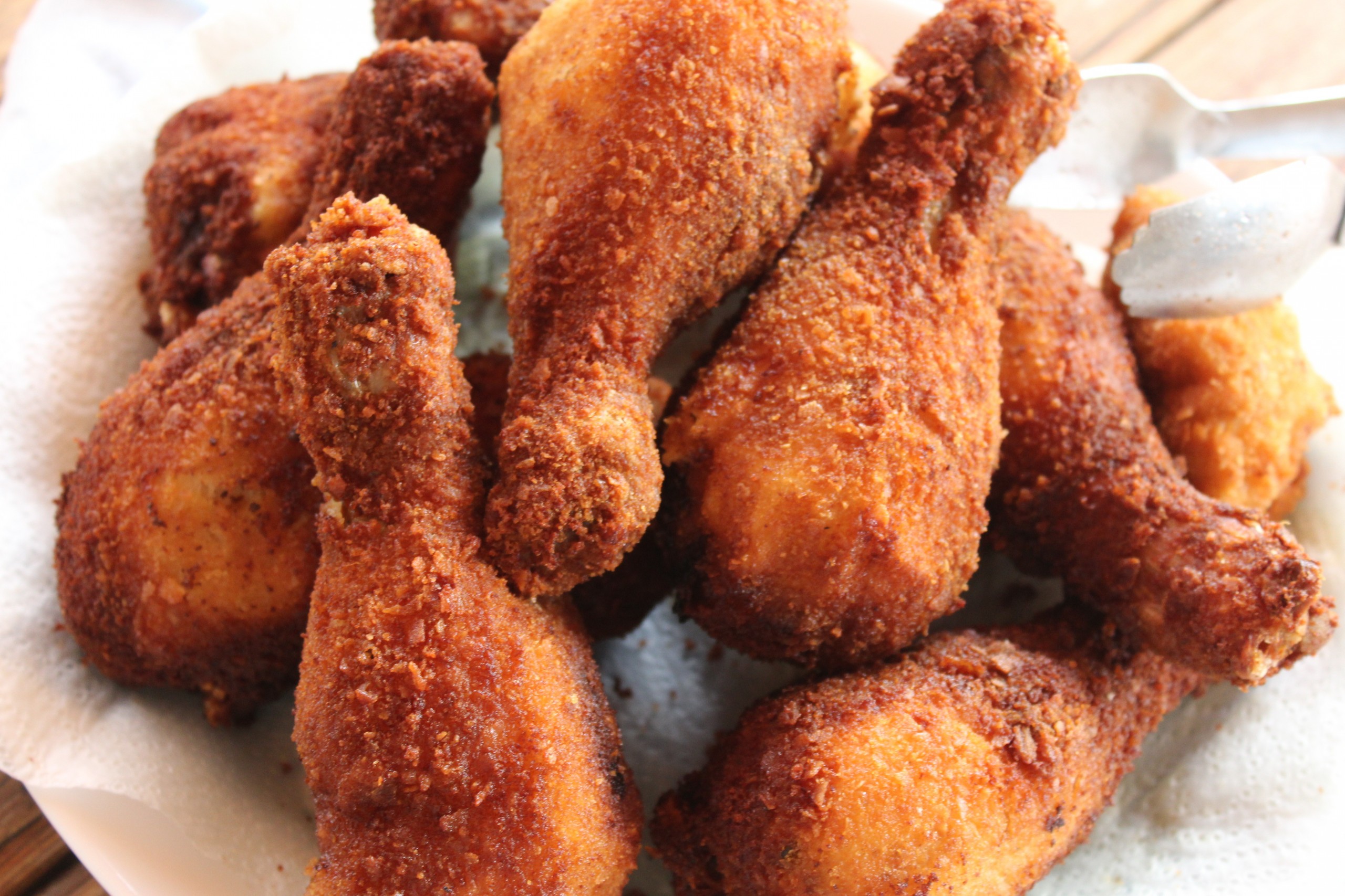 Pollo rebozado estilo americano KFC servido sobre tabla rústica con salsa BBQ y decoración de perejil fresco