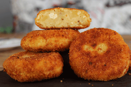 Hamburguesas de patatas y queso feta, apiladas una cortada por la mitad