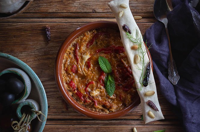 Sopa vasca zurrukutuna servida en cuenco de barro, decorada con menta fresca y acompañada de pan crujiente con piñones y guindilla