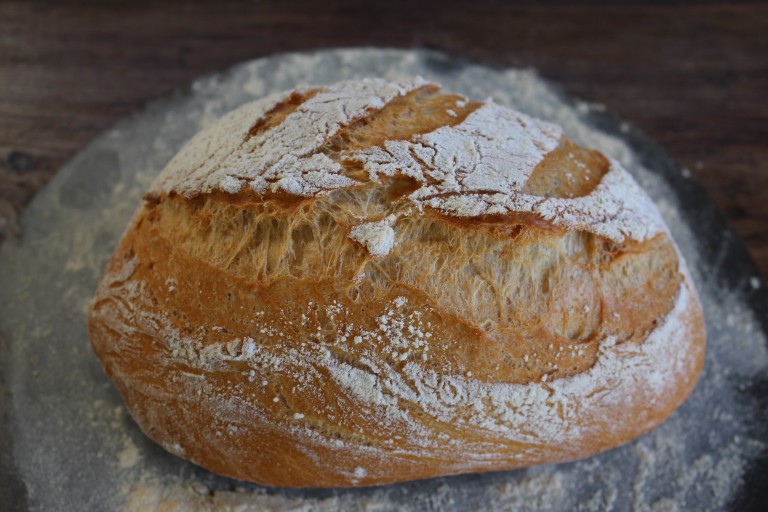 Pan artesanal de espelta con algas wakame, de corteza dorada y textura rústica sobre superficie enharinada.