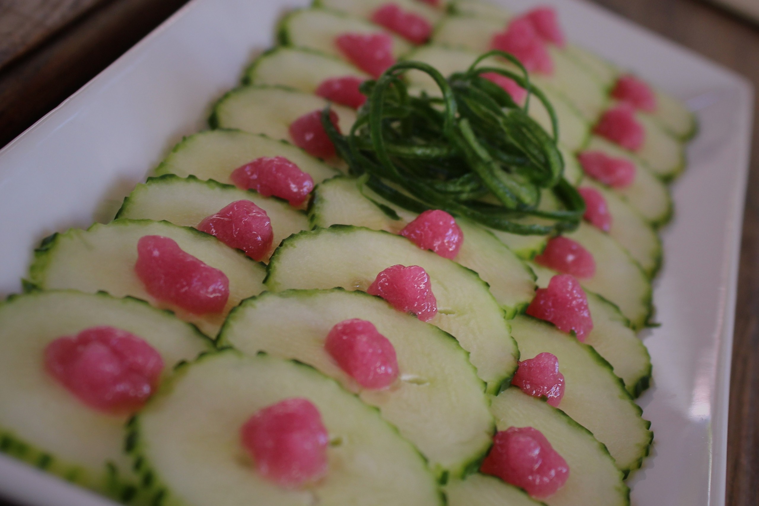 Aperitivo fresco con gel de cebollas rojas sobre pepino, ideal para entrantes creativos y cocina vegetal gourmet.