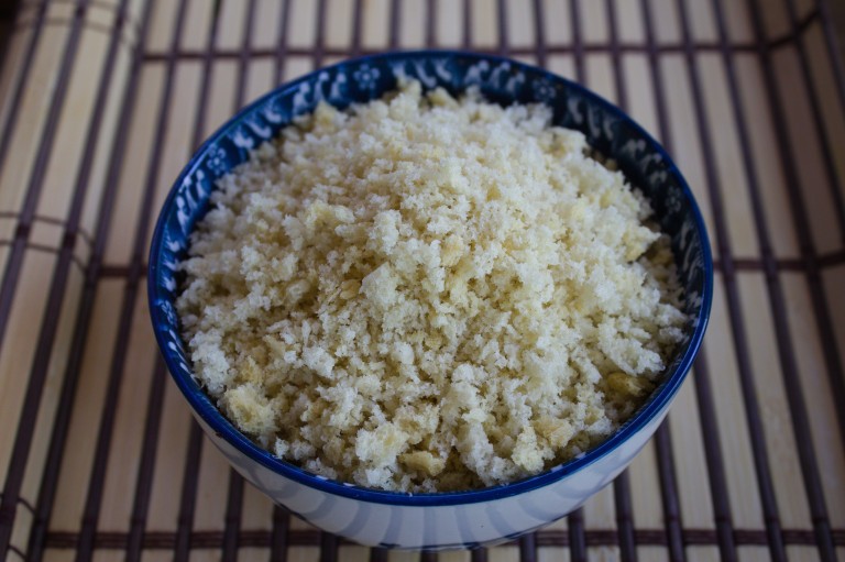 Pan rallado panko en un cuenco azul decorativo sobre esterilla de bambú, mostrando su textura ligera y crujiente.