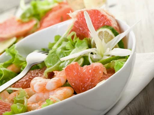 Ensalada fresca de pomelo y gambas con mezcla de lechugas variadas, servida con vinagreta cítrica.