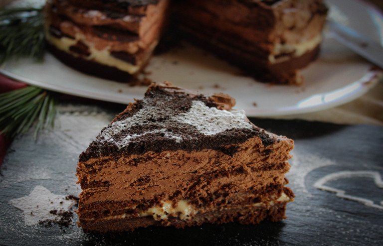 Tarta casera de chocolate con capas de dulce de leche y galletas Oreo decorada con azúcar glas.