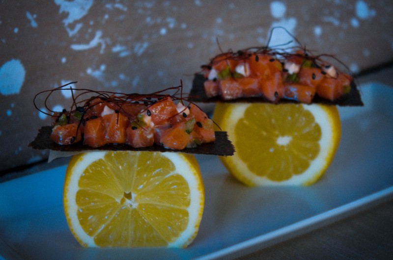 Tartar de salmón con ponzu y alga nori crujiente servido sobre rodajas de limón