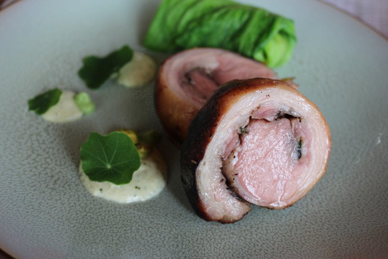Costillar de cordero relleno con centro rosado y guarnición.