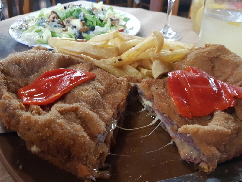 Cachopo asturiano auténtico relleno de jamón y queso fundido con pimientos del piquillo.